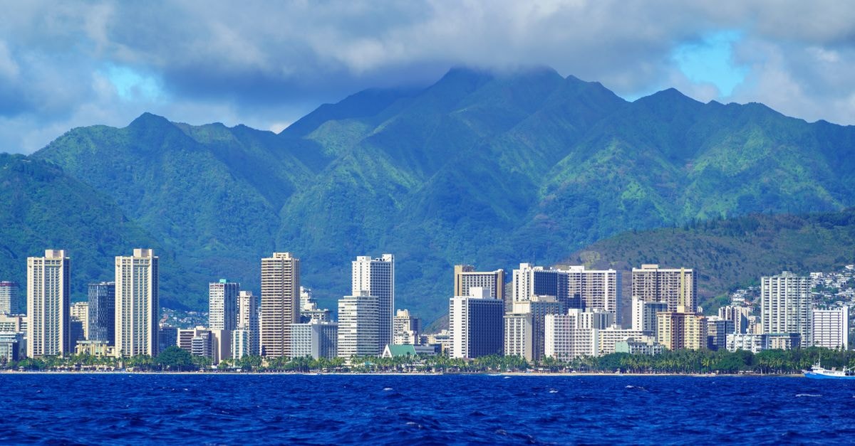 Stunning aerial view of Honolulu's skyline with lush mountains and ocean in foreground.
