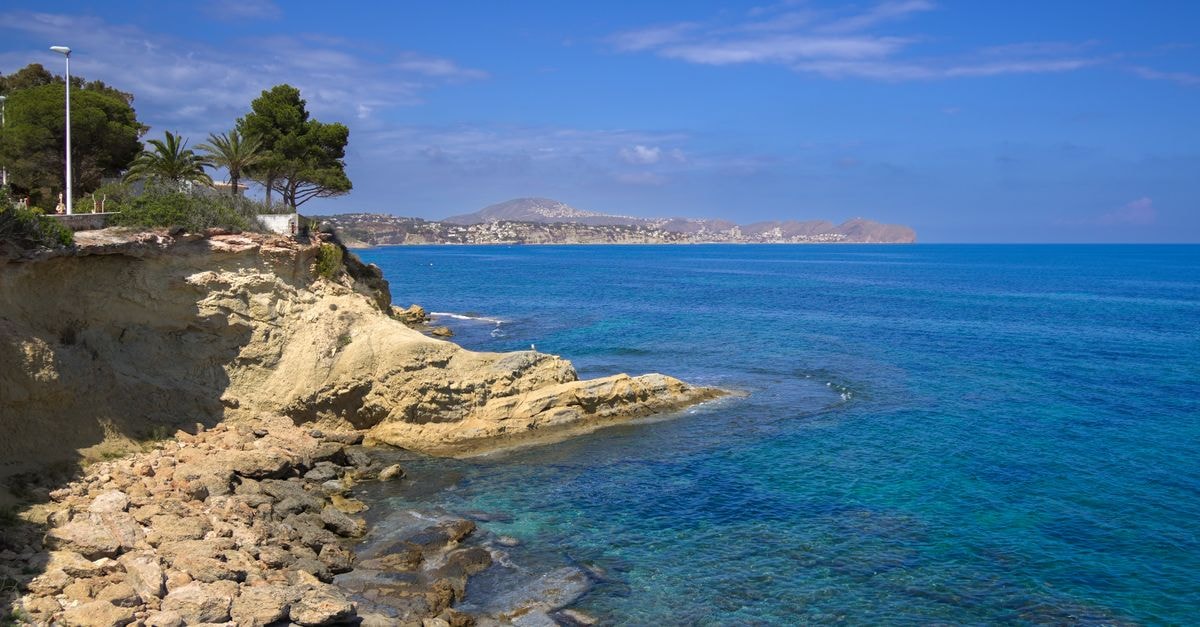 Alicante Travel Guide: Sun-Soaked Costa Blanca Essentials Beautiful coastal scene in Calpe, Spain with clear blue waters and rocky cliffs.