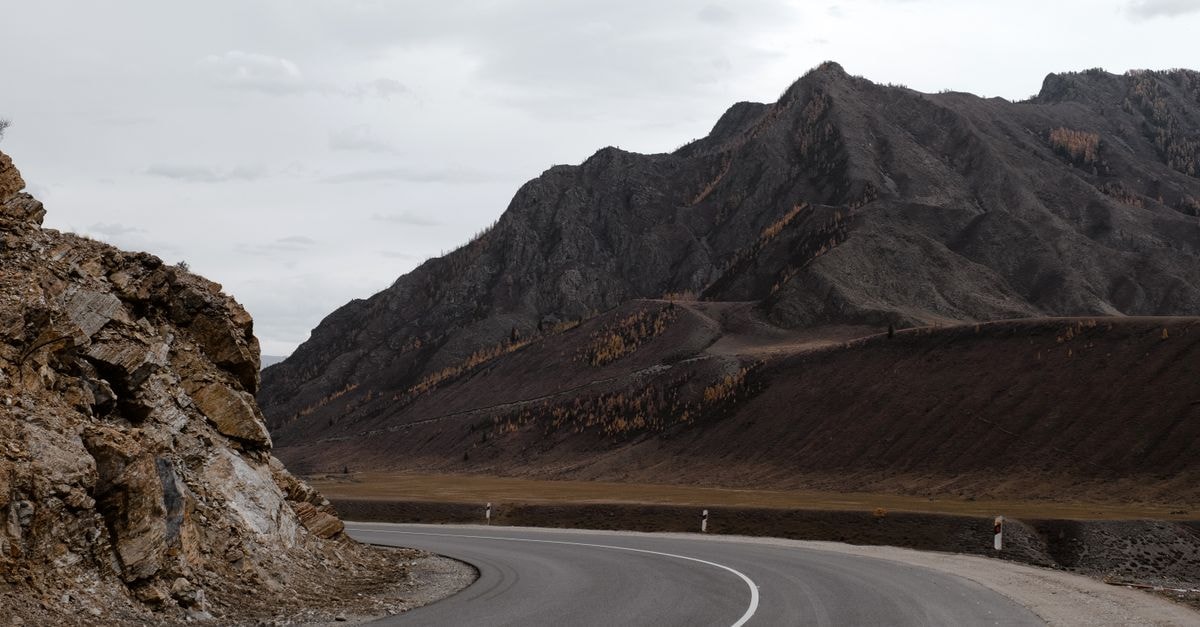 Dassa-Zoume Travel Guide: Sacred Rocks and Quiet Roads Curved asphalt road winding through rocky mountain scenery in Russia, perfect for travel and adventure themes.