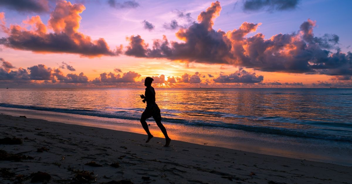 Mombasa travel guide: where the coast breathes slowly A lone jogger's silhouette on the sandy Mombasa beach during a vibrant, colorful sunrise.