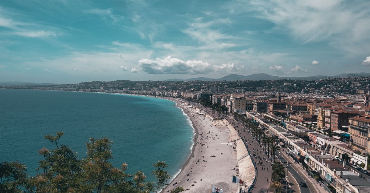 Stunning aerial view of Nice, France with bustling beachfront under a clear summer sky.