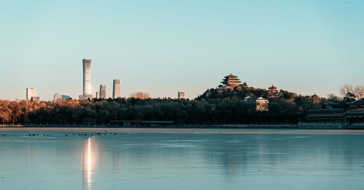 Super 8 in Beijing: A Financial Street Base Near the Forbidden City Beautiful view of Beijing's modern skyline and historic Beihai Park across a serene lake.
