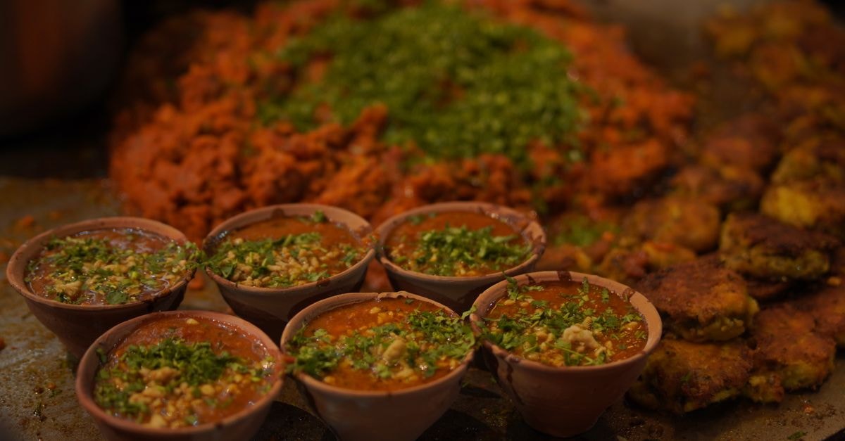 Close-up of Indian street food with vibrant toppings and spices in clay pots.