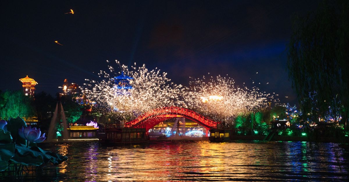 Discovering Xinxiang: A Slow-Travel Guide to Henan's Mountain City Stunning night view of a colorful bridge and fireworks reflected on a water surface in Kaifeng, Henan, China.
