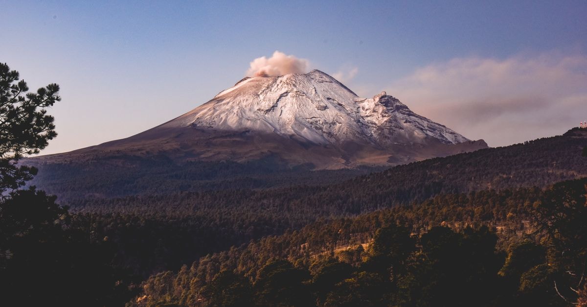 A Slow-Travel Guide to Colima, Mexico's Volcano Gateway Breathtaking landscape of Popocatépetl Volcano with snow-capped peak surrounded by lush forests in Puebla, Mexico.