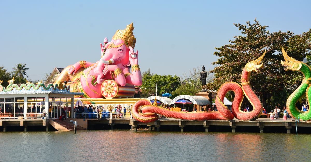 Samut Sakhon Travel Guide: Planning Tips, Costs and Things to Do Giant Ganesh and colorful serpent statues by a lake in Tambon Bang Kaeo, Thailand.
