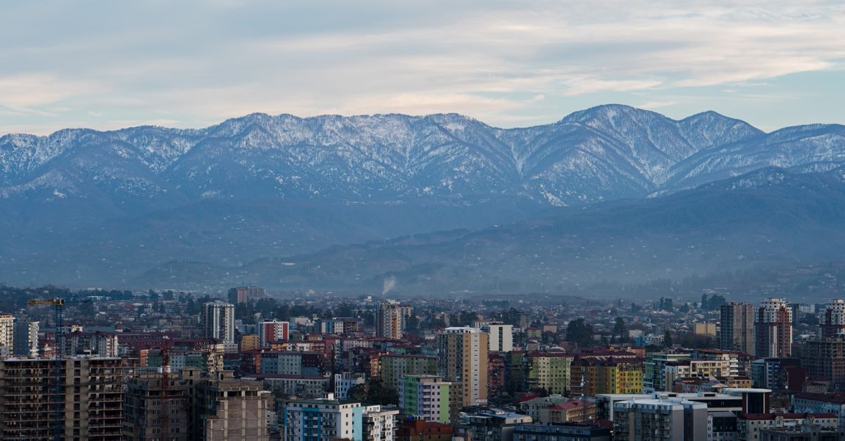 Nalut Hotel in Nalut: Gateway to the Nafusa Mountains Cityscape view with buildings and snow-capped mountains under a cloudy sky.