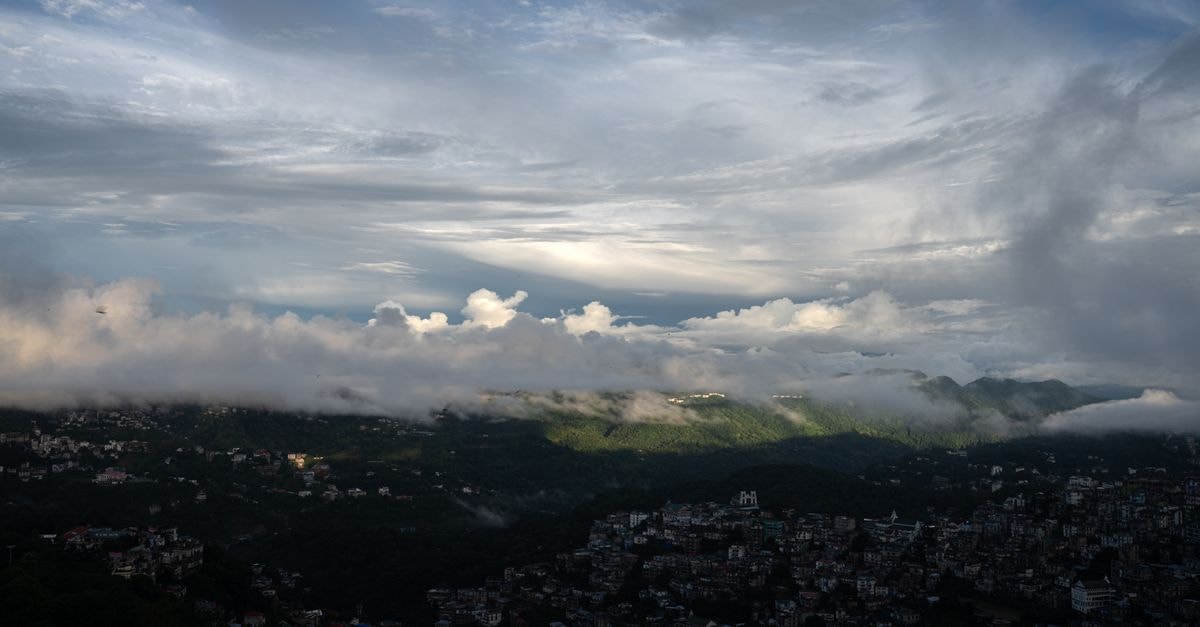 A la Maison, Shillong: Cosy Apartment-Style Stay on Laban East Road A breathtaking view of a city nestled in the mountains, covered in clouds at dusk.