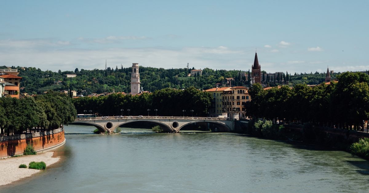 Picturesque view of Adige River flowing through Verona under a clear sky.
