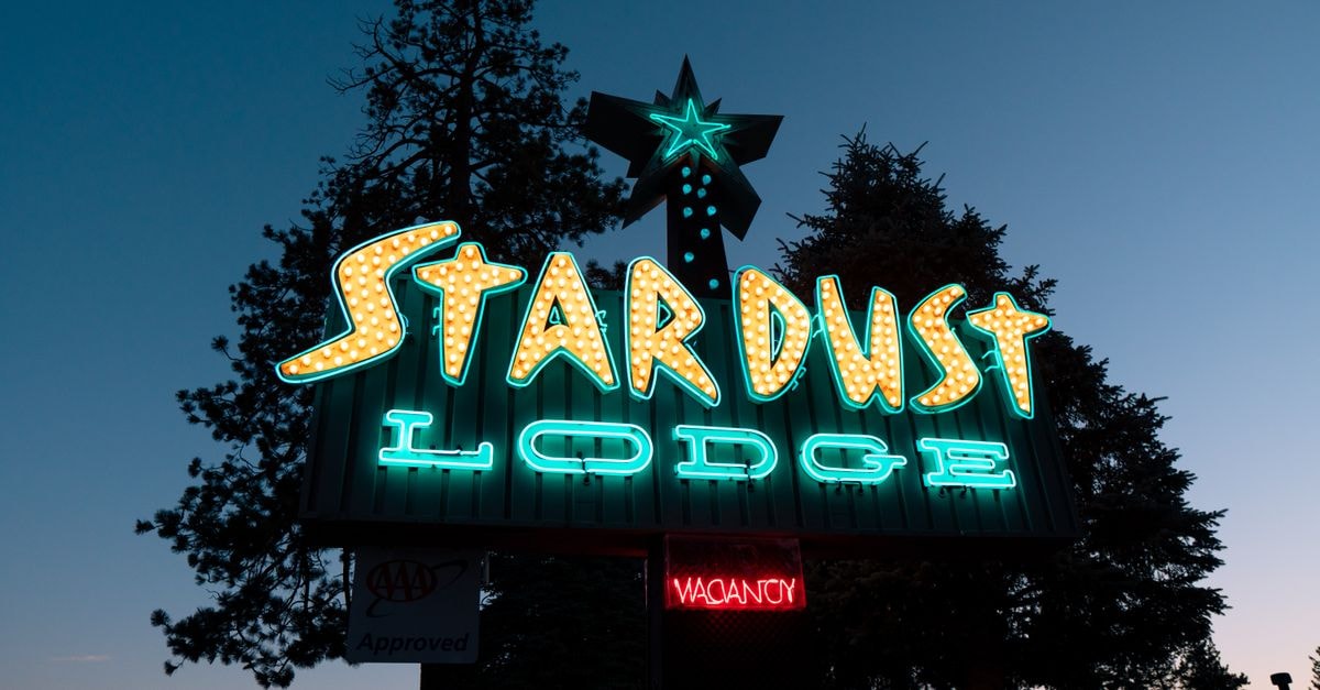 Lodge in Darbhanga: Riverside Stay on SH-50, Shastri Nagar Vibrant neon signage of Stardust Lodge in Tahoe City at dusk, surrounded by trees.