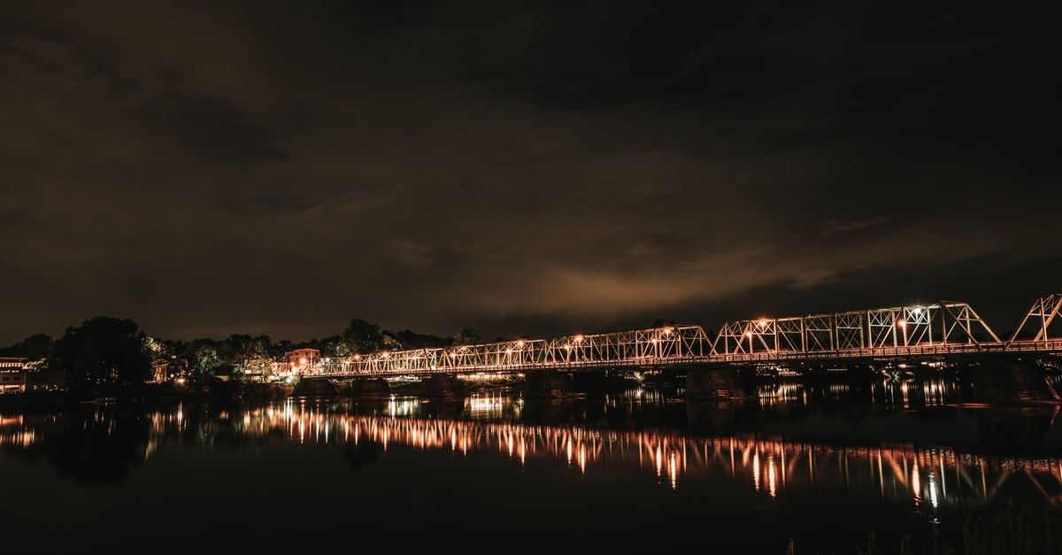 Comfort Inn in Fredericton: A Pet-Friendly Prospect Street Stay A serene nighttime view of an illuminated steel bridge reflecting on a calm river under a cloudy sky.