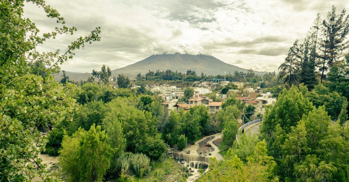 La Plaza Arequipa Hotel – Boutique Stay on Arequipa's Plaza de Armas Scenic view of Misti Volcano surrounded by lush greenery and a serene river in Arequipa, Peru.