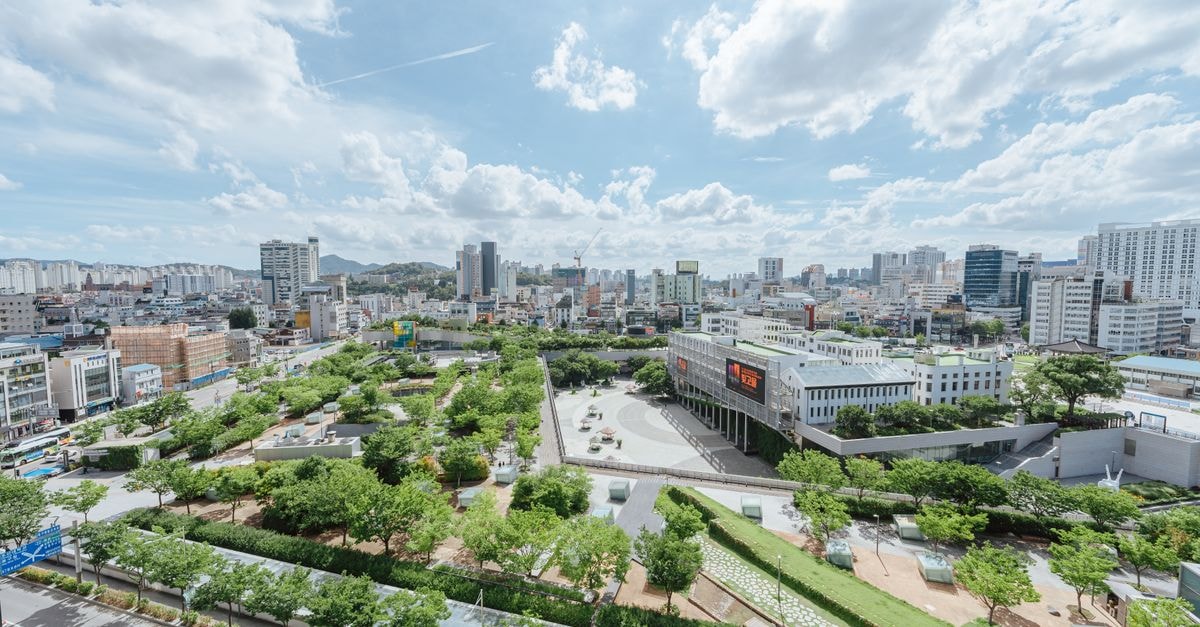 Hotel Golden Tulip Hail, Ha'il — A Practical Stop on Madina Road A vibrant cityscape featuring a lush urban park surrounded by modern buildings under a partly cloudy sky.