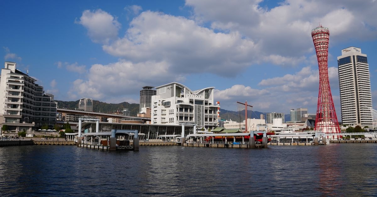 Kobe travel guide: hilltop views, harbor walks, and slow bites Beautiful waterfront view of Kobe Harbor with iconic red Kobe Port Tower under blue skies.