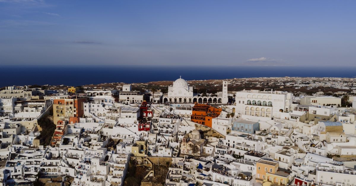 Villa Roussa in Fira: 150 m from the Caldera Sunset A stunning aerial view of Fira, Santorini showcasing iconic white architecture and the Aegean Sea.