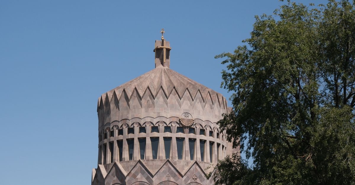 Yerevan Travel Guide: A Slow Look at Armenia's Pink City View of the distinctive dome of Etchmiadzin Cathedral against a clear blue sky, with lush greenery.