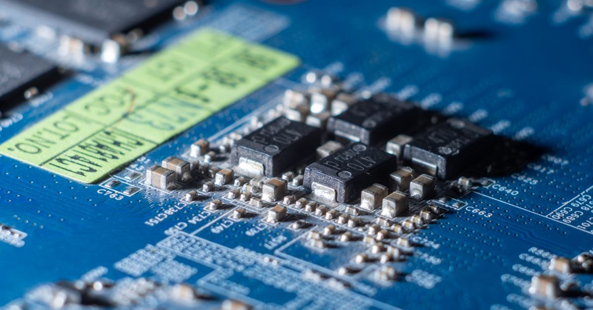 Detailed macro shot of a blue circuit board with multiple microchips and electronic components.