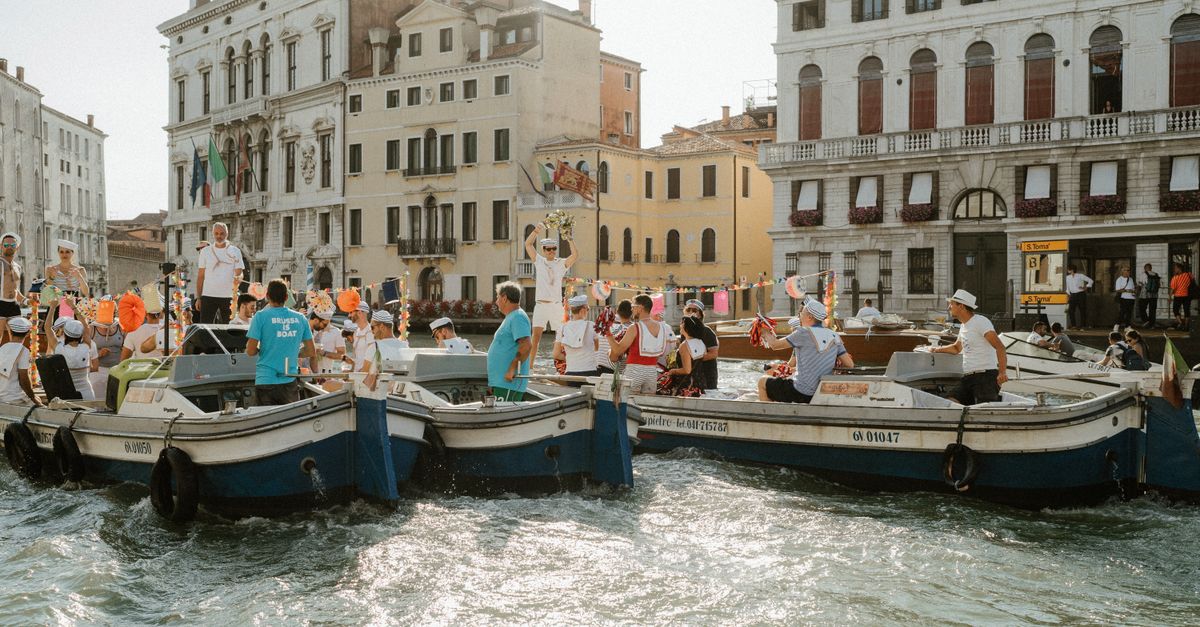 Venice Film Festival unveils 2026 lineup with Pattinson, Oasis and Musk documentaries Festive gathering on boats in Venice canal against historic architecture under bright daylight.