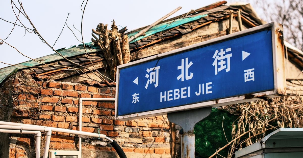 Siping Travel Guide: Quiet Corners and Railway Heritage in Southern Jilin Street sign for Hebei Jie in front of rustic brick building, China.