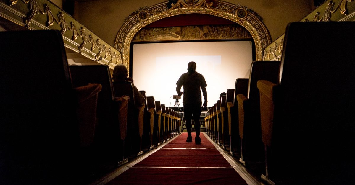 Florin Șerban's 'You Don't Belong Here' Wins Pardo d'Oro at 79th Locarno Film Festival A person walking down an aisle in a vintage theater, showcasing ornate decor.