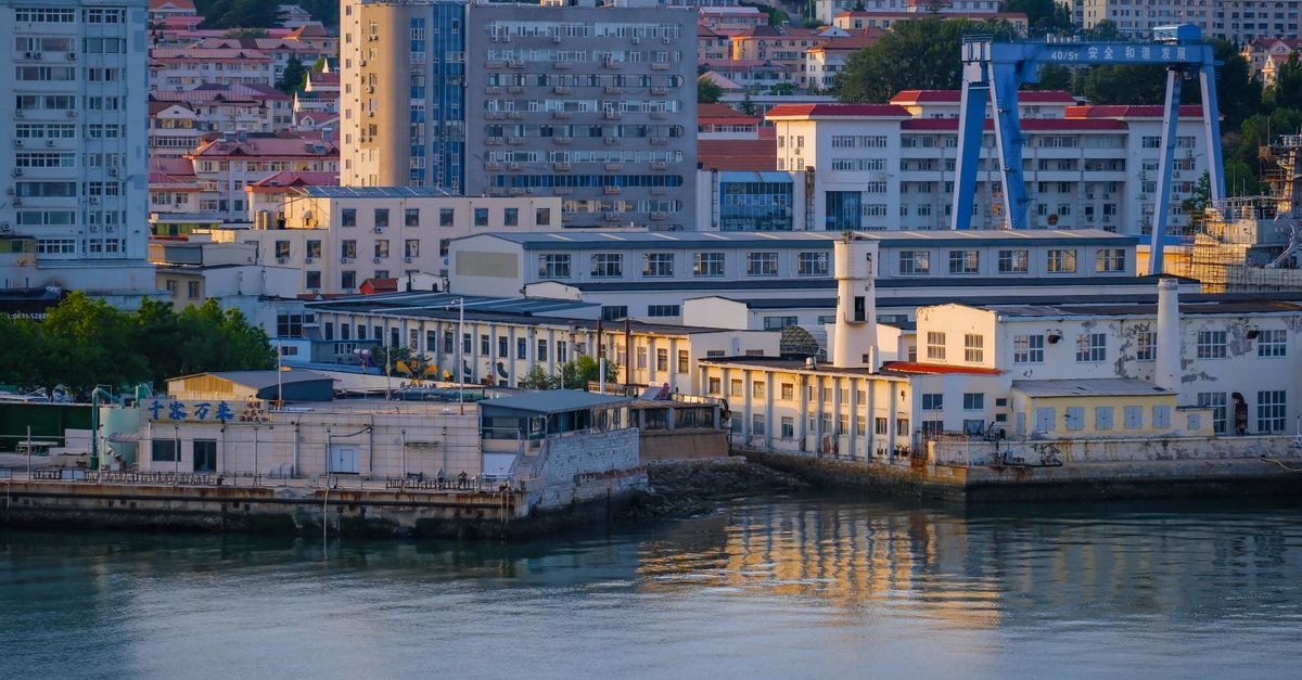 Hotel Lishui Yongli Business in Lishui: A Liandu District Address in Wanxiang A scenic view of city buildings and industrial structures along a calm waterfront during dusk.