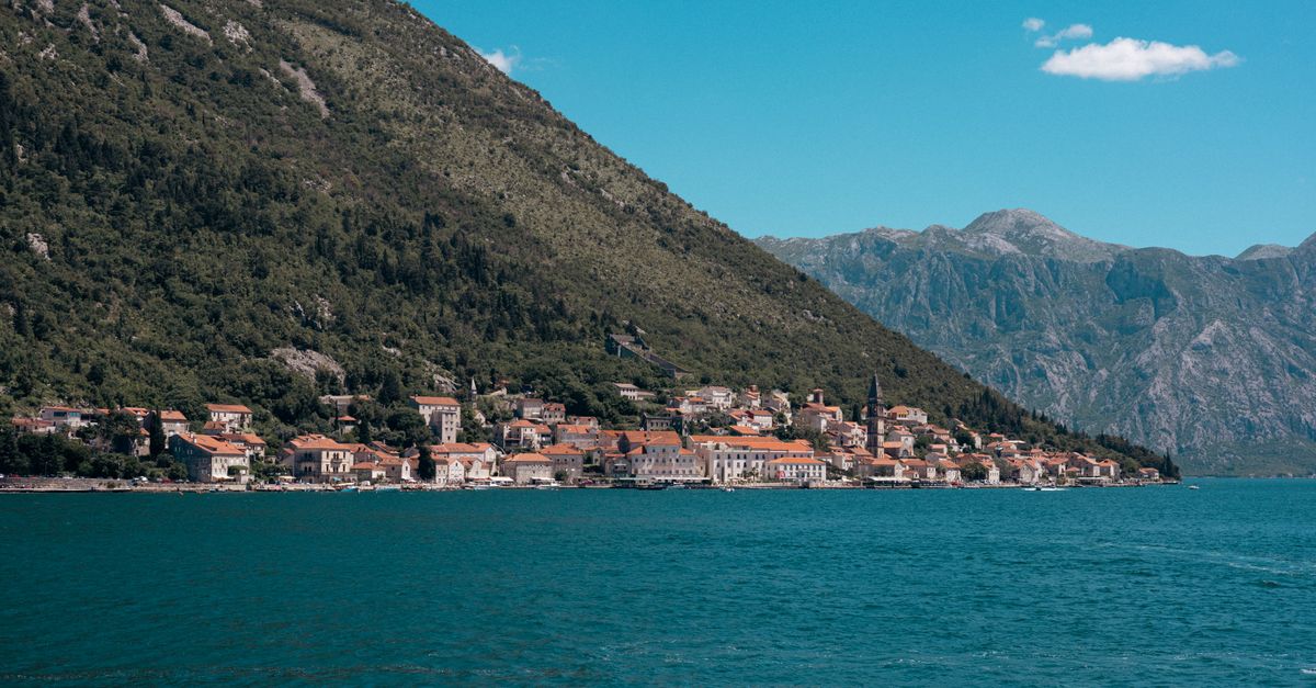 Kotor in July 2026: A Practical Travel Guide for the Bay of Kotor Beautiful seaside town along the Bay of Kotor with mountains and clear blue water.