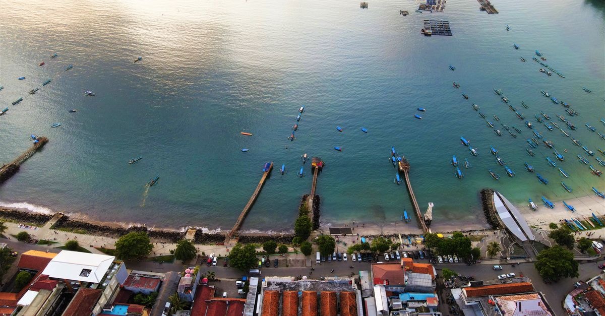 Situbondo Travel Guide: Java's Quiet Coastal Escape Stunning aerial shot of Pangandaran Beach in Indonesia showcasing jetties, boats, and vibrant shoreline.