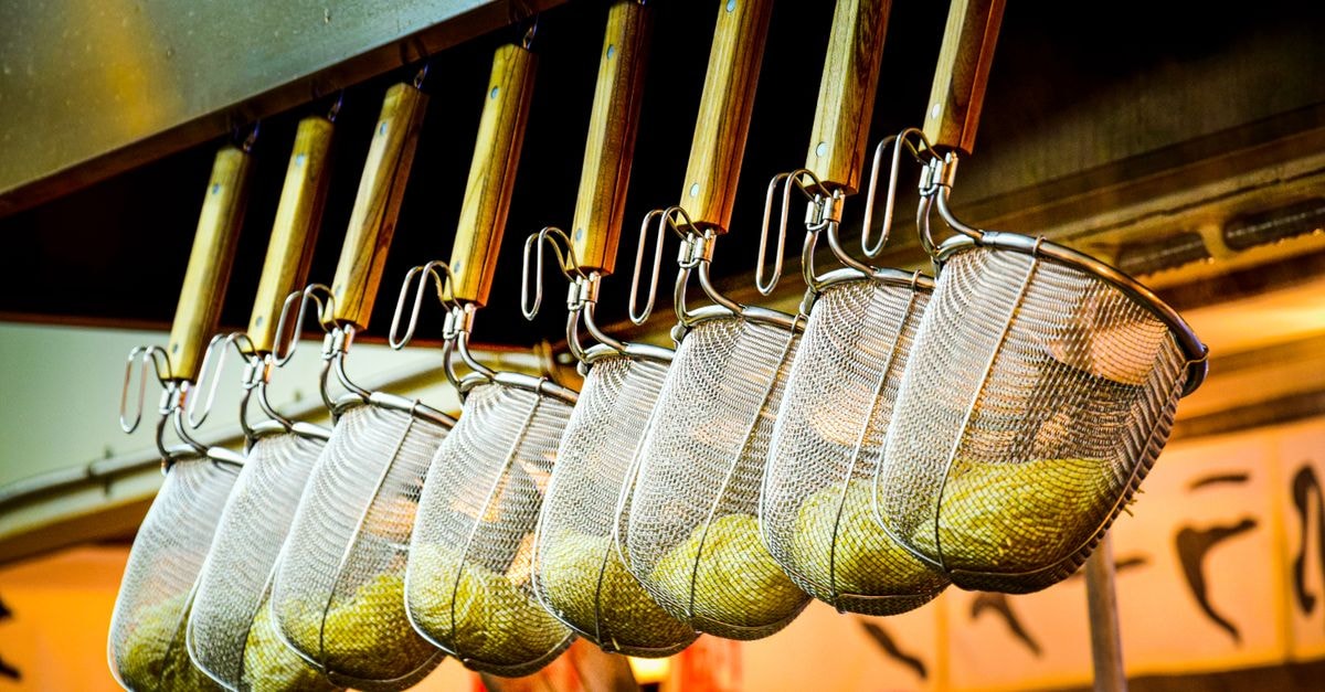 Morioka Travel Guide: Slow Days in Tohoku's Noodle Capital A close-up of noodle strainers hanging in a Japanese ramen restaurant, showcasing culinary tools.