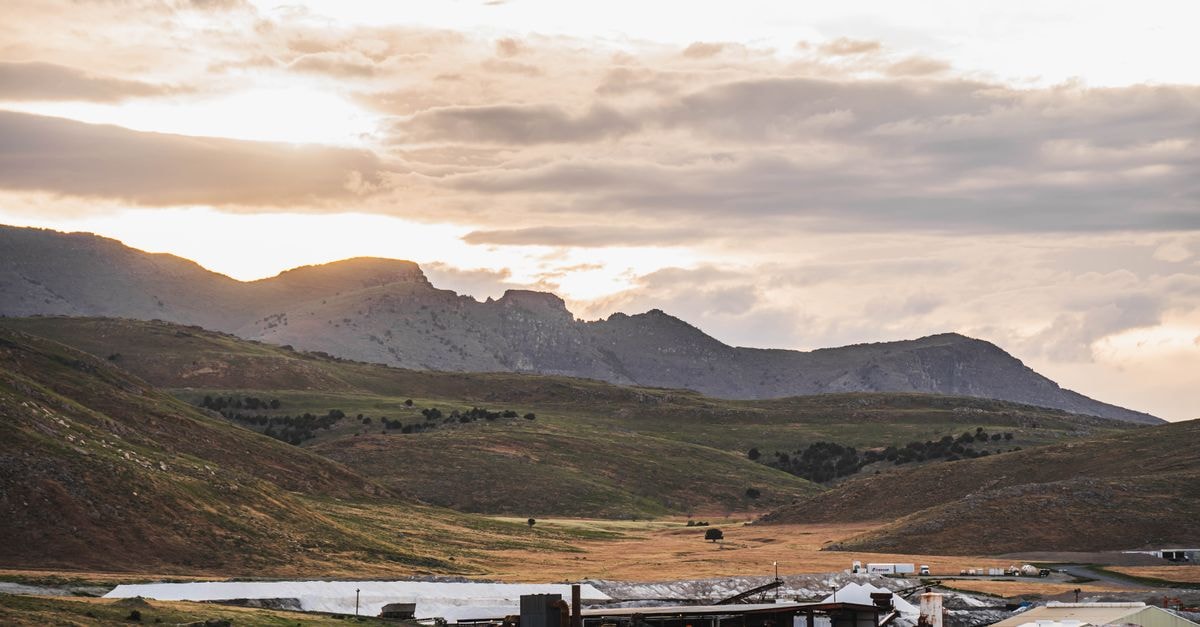Slow Mornings in Kapsabet: A Highland Town Travel Guide A scenic view of a mountain landscape with a settlement under a dramatic sunset sky.