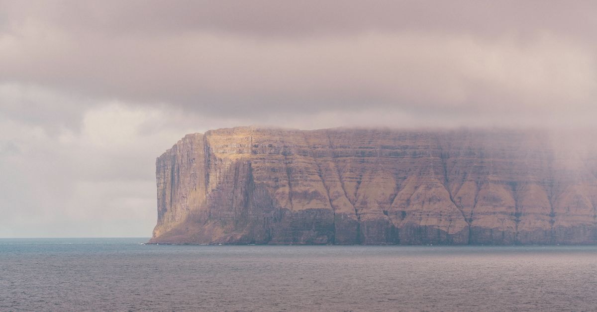 Tórshavn Travel Guide: A Slow Look at the Faroese Capital A stunning view of Faroese cliffs enveloped in mist, showcasing natural beauty and serenity.