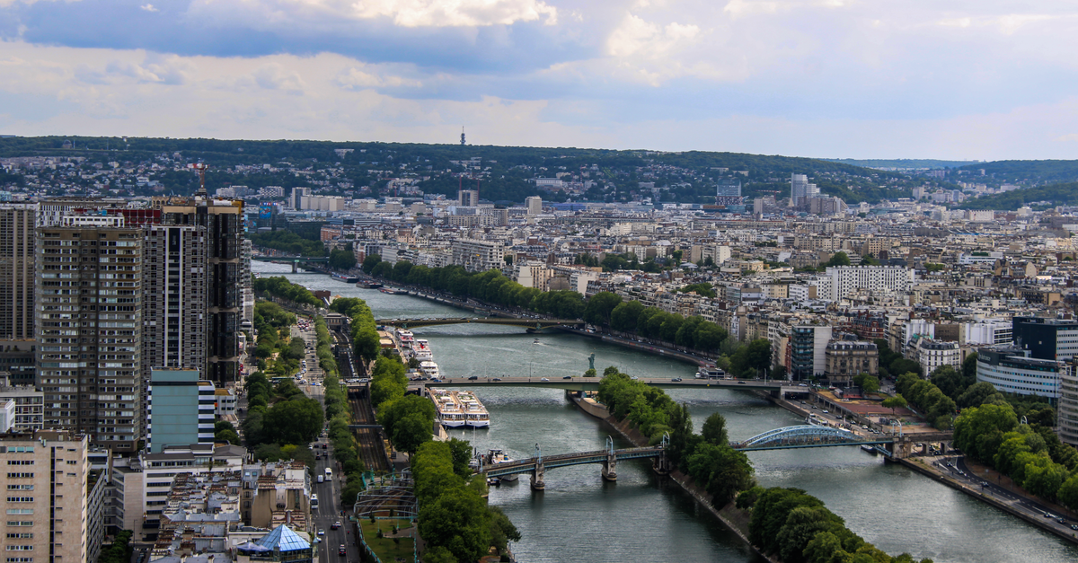 Rouen Travel Guide: A Quieter Normandy Capital by the Seine High-angle view of Paris featuring the Seine River and city architecture under cloudy skies.