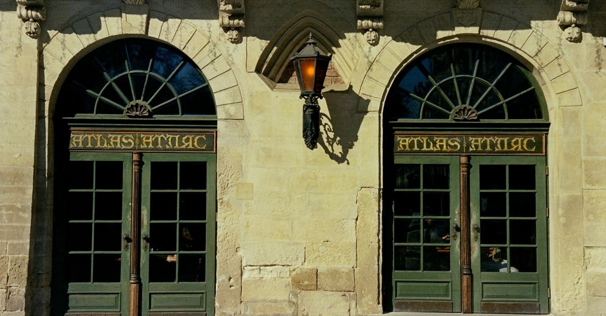 BANKHOTEL in Lviv: Restored 1912 Austro-Hungarian Bank Turned Boutique Stay Historic double-door entrance of Atlas Hotel in Lviv, showcasing exquisite architecture and classic design.