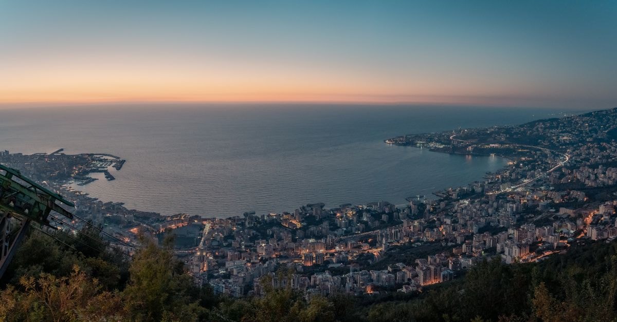 Riviera Hotel in Latakia: A City-Center Stay on 14 Ramadan Street A breathtaking aerial view of Harissa, Lebanon, with cityscape and coast at sunset.