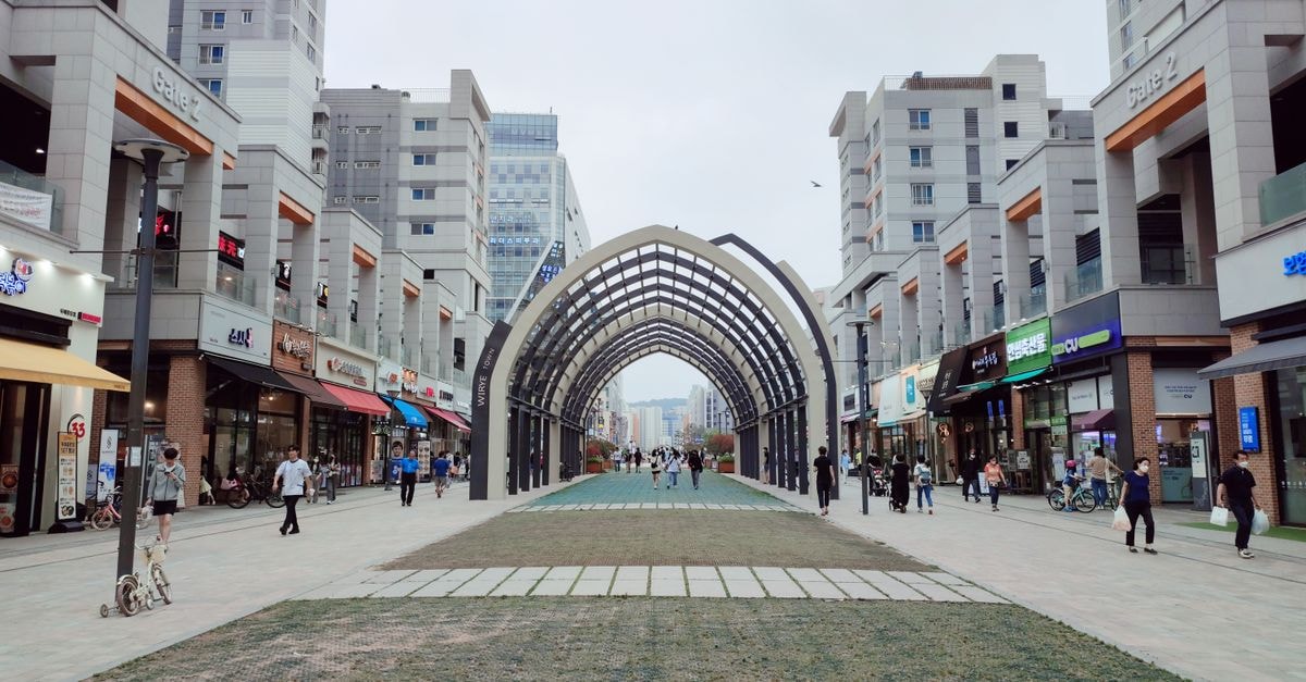 富川市旅遊指南:首爾旁的靜謐都市角落 人們在韓國河南市一座造型獨特的建築拱門下,穿過現代化的購物商圈。
