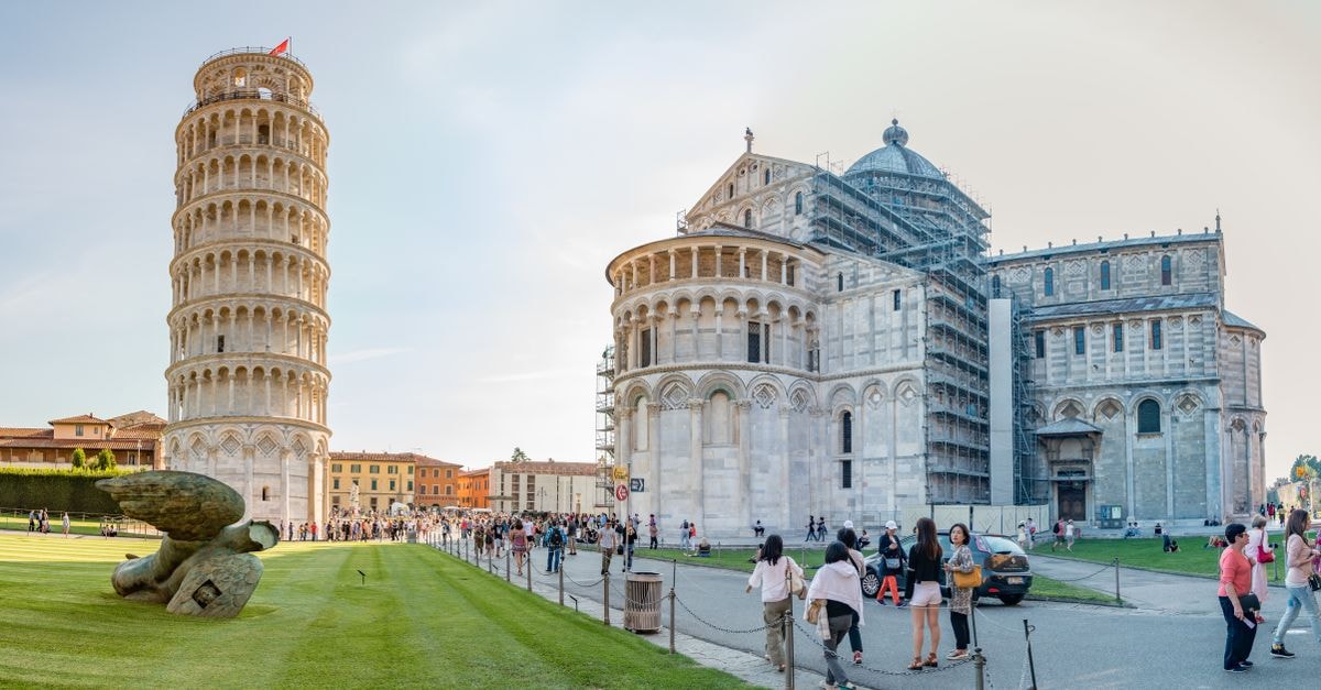 A Pisa Travel Guide for First-Time Visitors to Tuscany's Leaning City Leaning Tower of Pisa and Pisa Cathedral, Italy, with visitors in Piazza del Duomo under a clear sky.