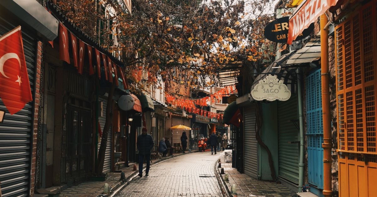 A picturesque view of a narrow street in Istanbul adorned with Turkish flags, capturing the vibrant city life.