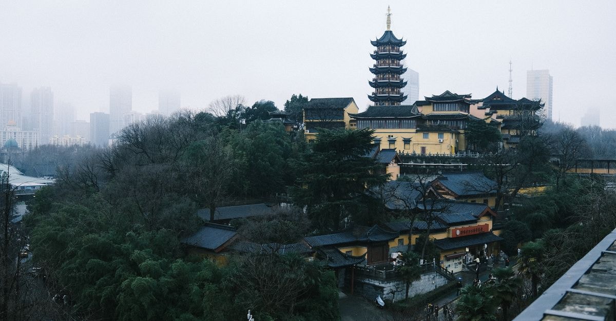 Xuchang Travel Guide: Ancient Wei Roots, Tobacco Country Dramatic view of an ancient pagoda in Nanjing, China, with urban skyscrapers in the misty background.