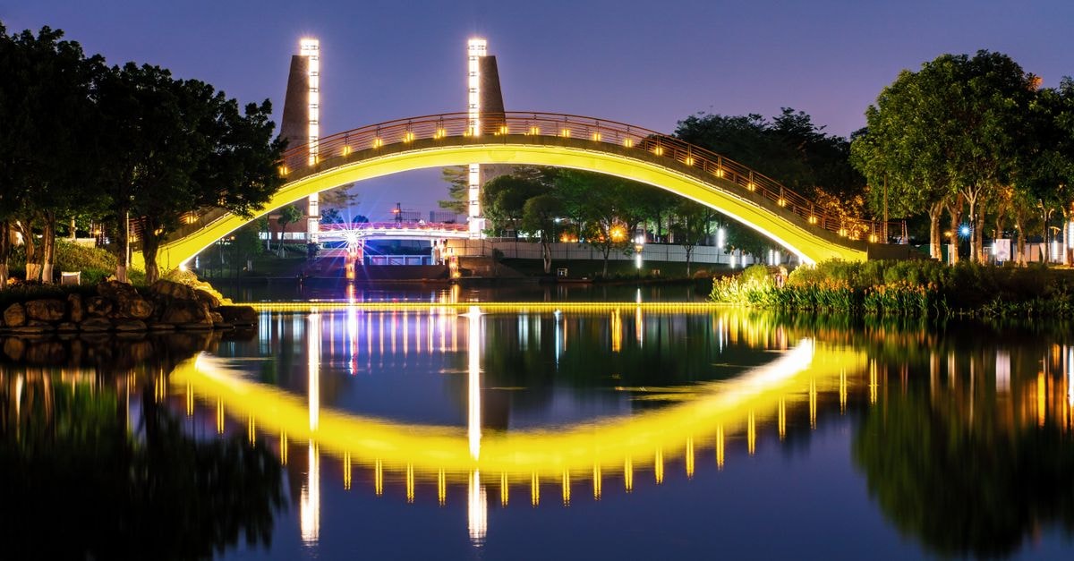 A stunning view of an illuminated bridge reflecting in the river at night in Foshan, Guangdong, China.
