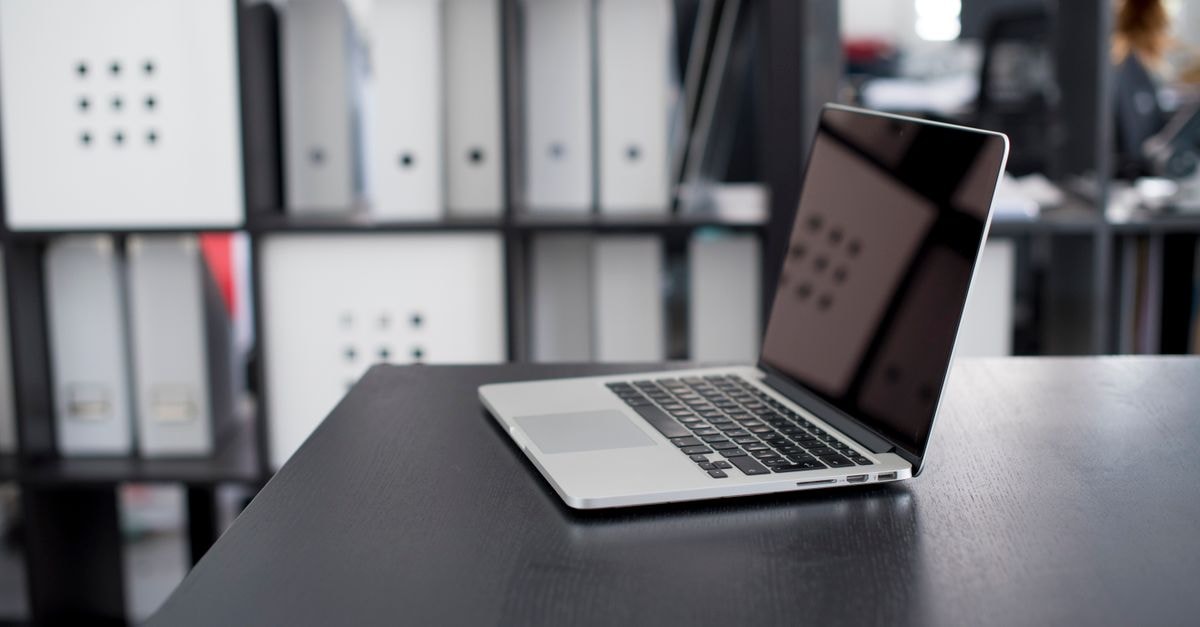 Apple Poised to Launch First New Mac Mini in Nearly Two Years MacBook Pro displayed on a minimalist office desk with shelves in the background.