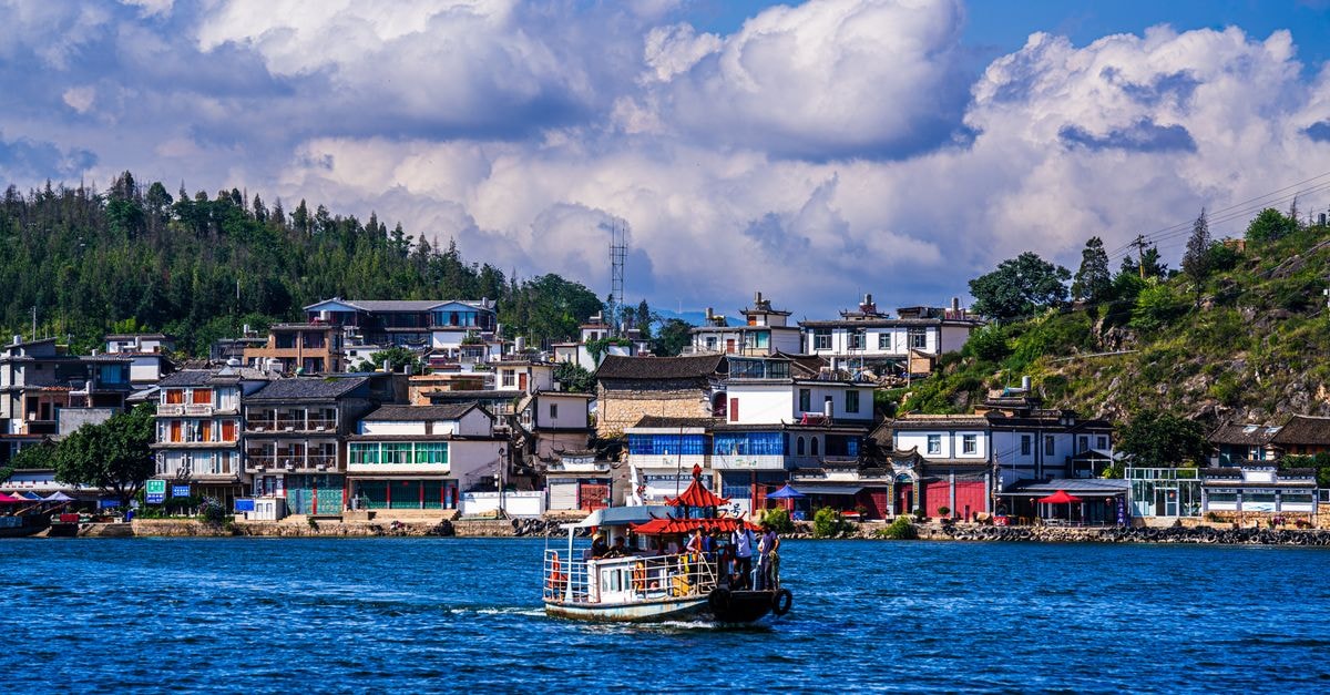 Quzhou Travel Guide: Planning Tips, Costs and Things to Do A picturesque village by the water with a traditional boat and vibrant buildings. Perfect for travel and culture themes.