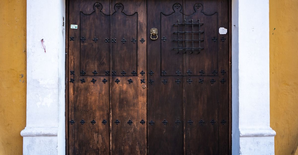 Gomez Palacio Travel Guide: A Quiet Doorway to the Laguna Ornate wooden door with iron details in Antigua Guatemala, featuring vibrant colonial architecture.