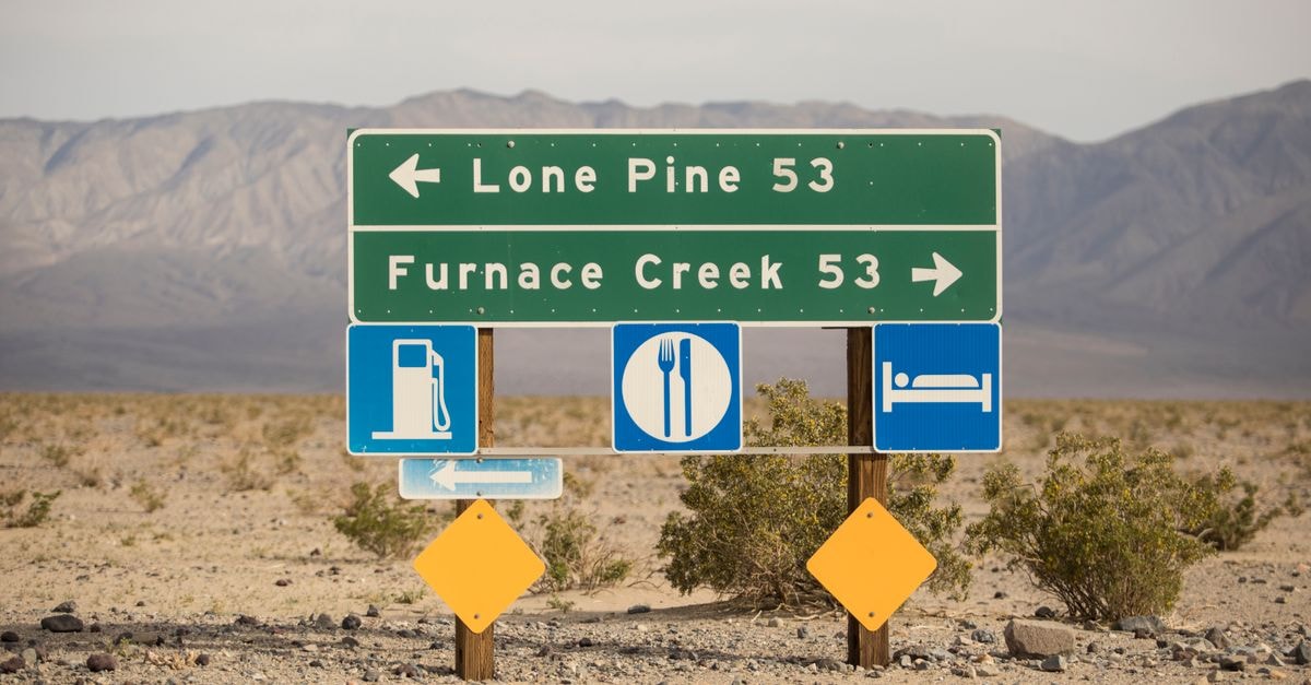 Signpost in desert landscape showing directions to Lone Pine and Furnace Creek in Death Valley.