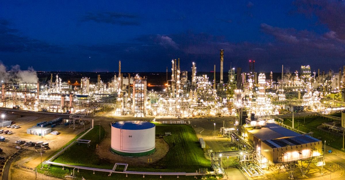 Chevron to invest $7 billion in Venezuela, aiming to double oil output to 600,000 barrels a day Aerial night view of a brightly lit industrial oil refinery with smoking chimneys in Rosemount, MN, USA.