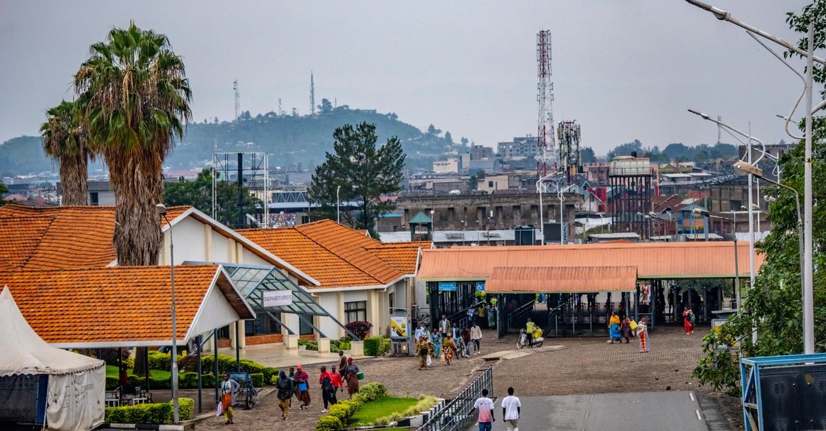 Mbuji-Mayi Travel Guide: Quiet Rhythm of the Diamond City Vibrant urban scene with people around orange-roofed buildings against a hilly backdrop.