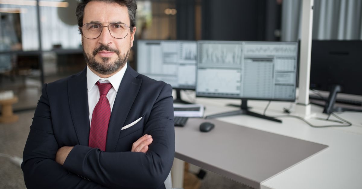 Broadcom CEO Rejects AI Slowdown Calls, Reaffirms $115 Billion Fiscal 2027 Revenue Target Business professional in corporate attire with arms crossed in a modern office space.