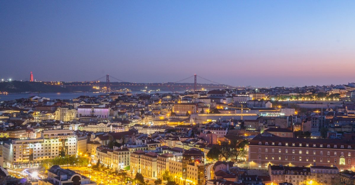 Vincci Baixa Suites Apartments, Lisbon — Riverside Address in the City of Seven Hills Scenic view of Lisbon cityscape at twilight, featuring lights, skyline, and historic architecture.
