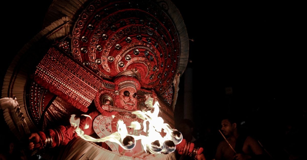 Kollam Travel Guide: Planning Tips, Costs and Things to Do A captivating Theyyam performance featuring vibrant costumes and fire rituals under the night sky.