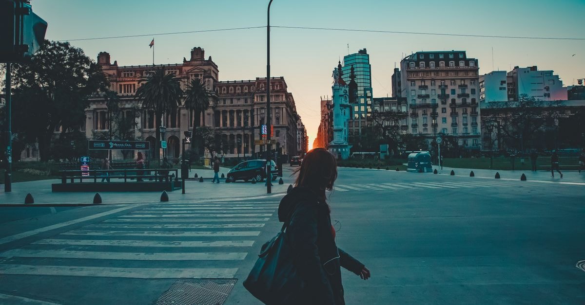 Rosario, Argentina Travel Guide: Riverfront Soul and Slower Evenings A person crossing a street in San Nicolás, CABA, Argentina during dusk with urban architecture in view.