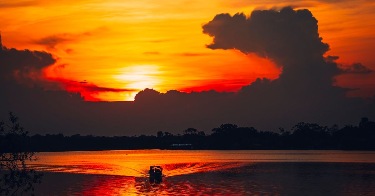 伊斯梅利亞旅遊指南:提姆薩湖上的日落 壯麗的夕陽倒映在湖面上,呈現出絢麗的色彩,水中央有一艘孤獨的小船剪影。