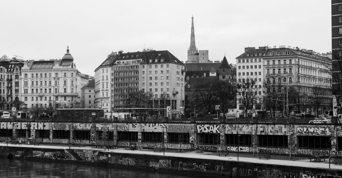 Pension Neuer Markt in Vienna: A Cosy Stay in the Herrnhuterhaus Monochrome view of Vienna cityscape featuring historic buildings and graffiti by the river.